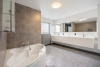Ensuite badkamer met hoekbad, douche en dubbele lavabo in fraai badkamermeubel 