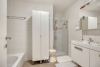 Betegelde badkamer met ligbad, douche en dubbele lavabo in badkamermeubel 